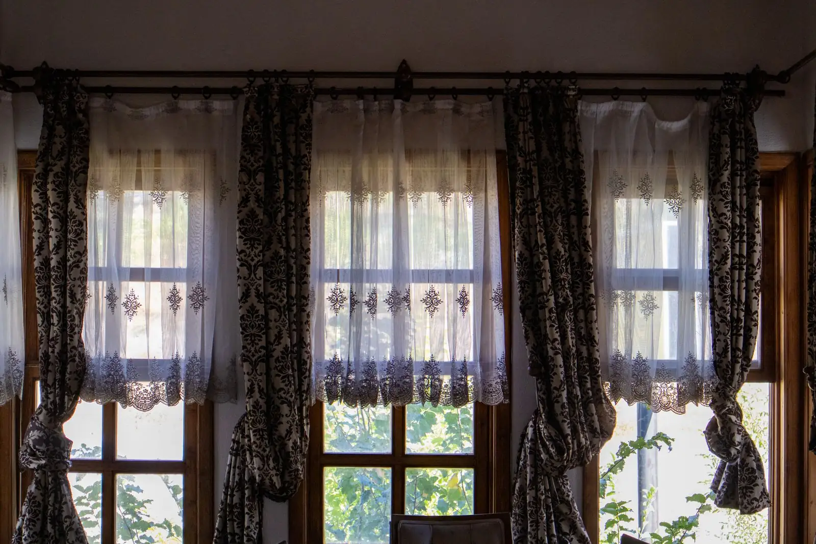 Tall windows dressed with patterned drapes and sheer curtains