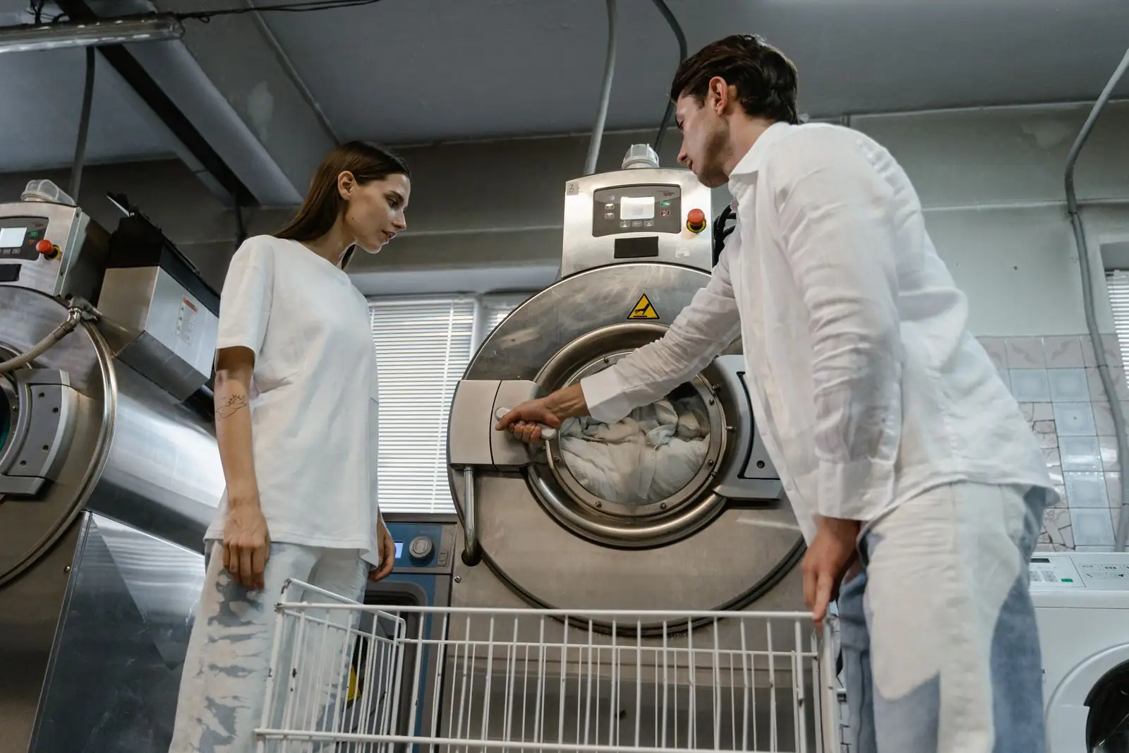 Two laundry workers loading a commercial washing machine
